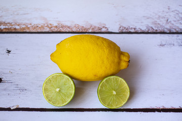 Fresh whole lemon and sliced lime on a white background.