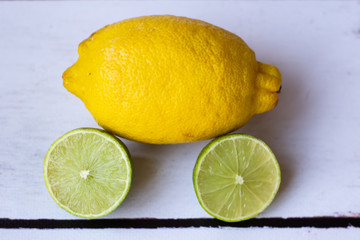 Fresh whole lemon and sliced lime on a white background.