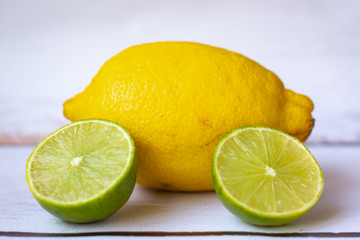 Fresh whole lemon and sliced lime on a white background.