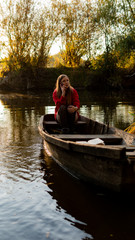 Fototapeta na wymiar curly girl sitting on the edge of an abandoned wooden boat at sunset.