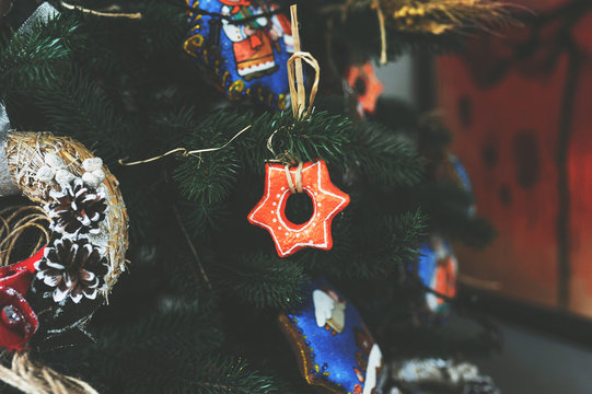 Close up photo of christmas tree branch with orange star toy on it with other toys as a beautiful holiday background, copy space for text