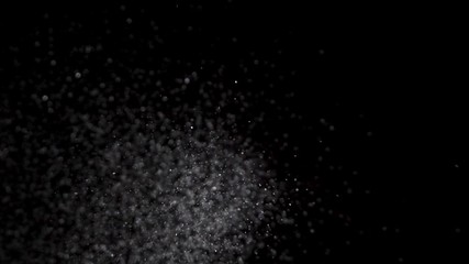Crystal glitter salt being dropped in slow motion on a black background
