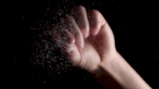 Salt crystals powder being dropped in slow motion on a black backdrop