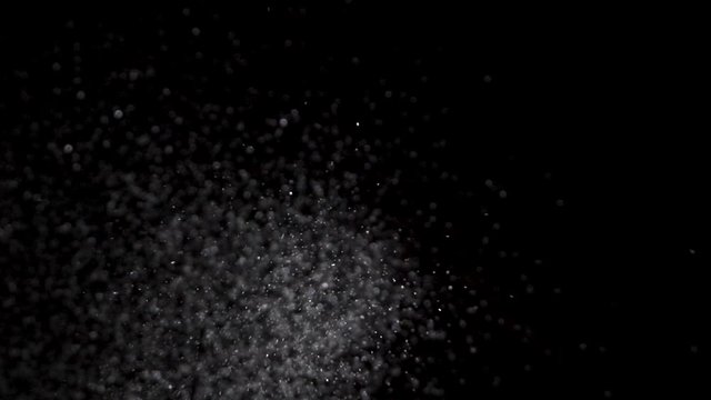Crystal glitter salt being dropped in slow motion on a black background