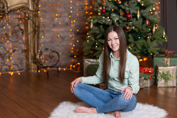 portrait of a fashionable young blue-eyed brunette in a light knitted sweater and blue jeans. 2020