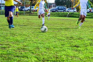 Obraz premium three young football players. Children play a soccer game. Legs in action with a ball.