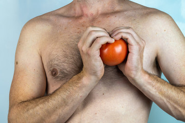 caucasian man without shirt with a tomato in his hand isolated on White background