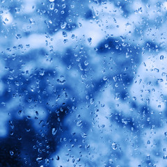 Abstract background with rain drops on window glass and classic blue blurred background. Color of 2020