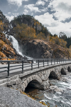 Beautiful landscape of nature in Norway, double latefossen waterfall by the road with an arched bridge in the forest and the river