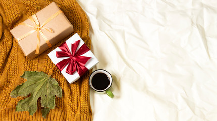 coffee cup and gift boxes, woolen scarf on bed, hello winter and christmas concept