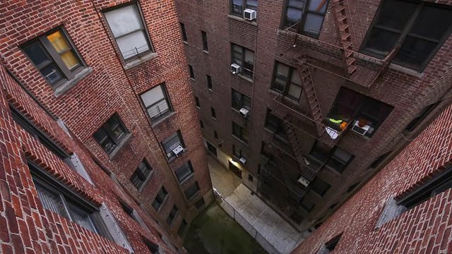 Cinemagraph of Aerial high angle looking down view of illuminated brick apartment condo building in Fordham Heights center, Bronx, NYC, Manhattan, New York City with fire escapes windows