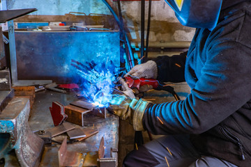 Worker in welding mask at factory. Welding process. Electric welding. Bright yellow sparks.