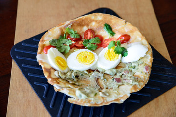 Flatbread with cooked eggs, tomatoes, cilantro and guacamole