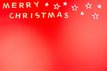 Naklejka premium The Inscription Merry Christmas made of wooden letters, lying flat from above, isolated on a red background.