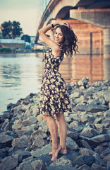 beautiful girl in dress, stones on the shore, bridge