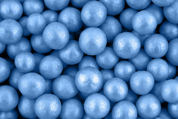 Candy sugar pearls, cake decoration, copy space. Small silver sparkle balls texture. Classic blue background. Color of the year 2020. Top view, flat lay