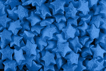 Candy sugar stars, cake decoration, copy space. Small sparkle balls texture. Classic blue background. Color of the year 2020. Top view, flat lay