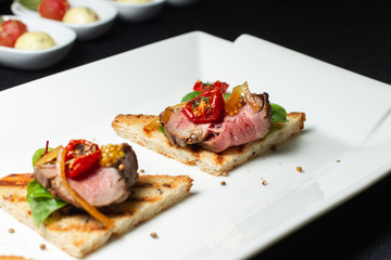 Italian sandwiches - bruschetta with meat, arugula, sun dried tomato and seeds on bread.