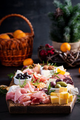 Antipasto platter with ham, prosciutto, salami, cheese,  crackers and olives on a wooden background.  Christmas table.