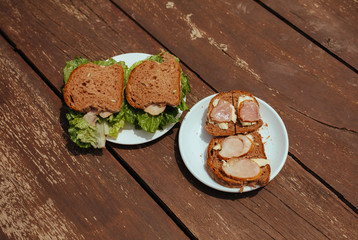 Sandwich with Hum and salad on a wooden bench