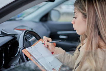 Fototapeta na wymiar business woman in the car writing down a reminder on her agenda