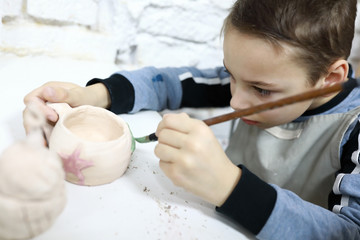 Child painting clay cup