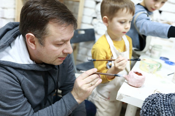 Father with sons paint clay pots