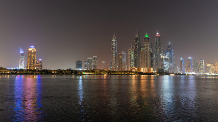 Obraz premium Dubai skyline at night with lights on the water and luxirious skyscrapers of UAE