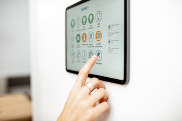 Controlling home with a digital touch screen panel installed on the wall. Close-up on a screen with...