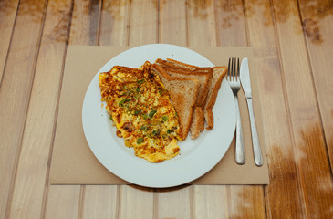 Omelet with vegetables and bread toast on white a plate