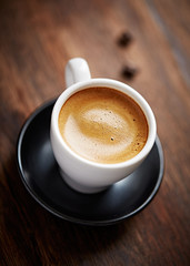 Cup of coffee with amaretti (Italian biscuit) on rustic wooden background. Close up.