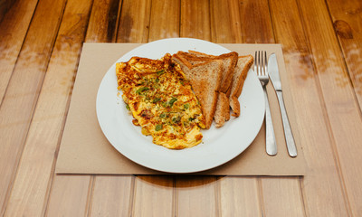 Omelet with vegetables and bread toast on white a plate