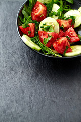Salad with Tomatoes, Cucumber and Rocket on stone Background. Healthy Snack Idea. Close up. Copy space.