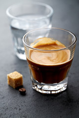 Coffee in glass cup on dark stone background.