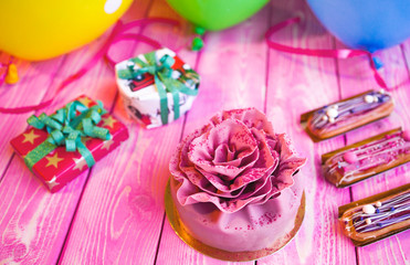 Pink cake Birthday, Valentines Day, presents and colorful balloons on a light pink wooden board. Concept celebration.