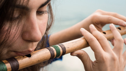 Musician playing a wooden flute on the banks of the river © afanasyeva_t