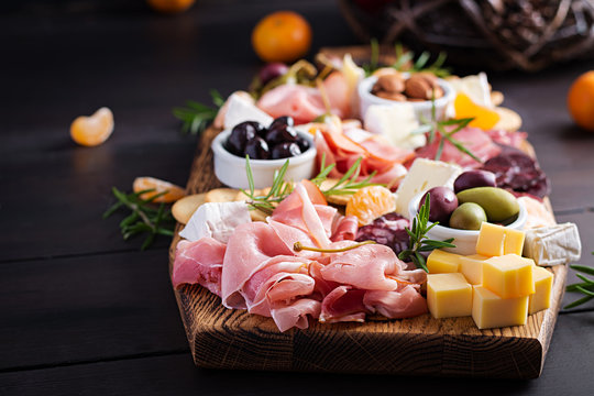 Antipasto platter with ham, prosciutto, salami, cheese,  crackers and olives on a wooden background.  Christmas table.