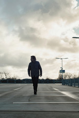 Man inspecting parking lot with cloudy sky.