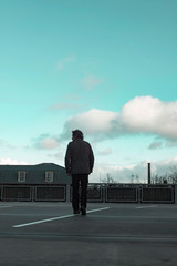 Man in green jacket inspecting parking lot.