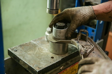 hands of a mechanic changing the silent block in the hydraulic press
