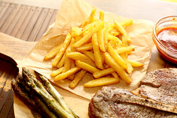 Pommes frittes auf backpapier mit spargel und steak