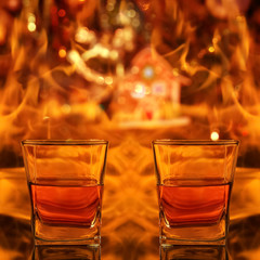 Background with flames and Christmas decorations. Two full glasses of whiskey.