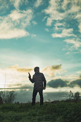 Man with handgun in countryside at sunset.