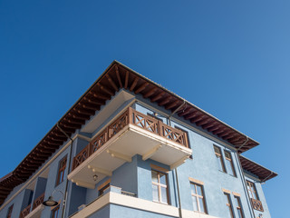 Corner balcony of a building of blue color with a blue sky background