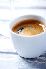 Cup of coffee on white wooden background. Close up. 