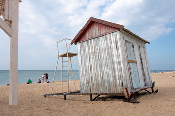 The empty beach on the sea in autumn with a small abandoned cloakroom. Cloudy sky in the afternoon