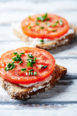 Tomato sandwich with cream cheese on white wooden background. Close up.
