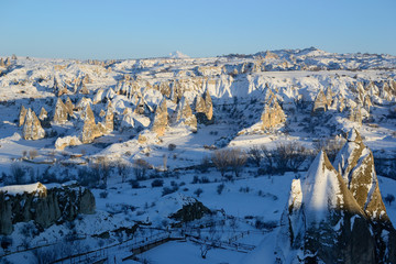 Beautiful snowy winter view of unusual rock formations in Cappadocia near Goreme before sunset