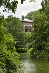 Fototapeta na wymiar Baie vitrée d'un des musées émergeant de la nature luxuriante de l'étang du parc Léopold à Bruxelles