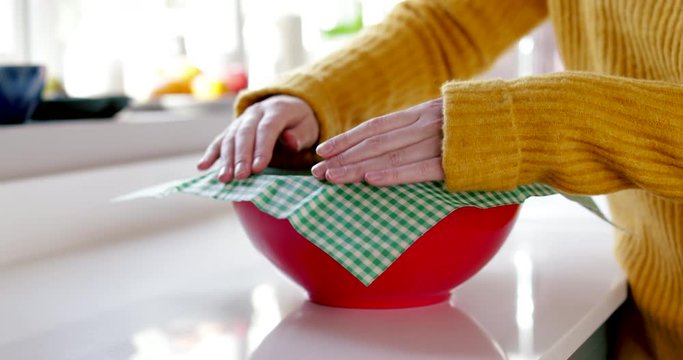 Close Up Of Woman Wrapping Food Bowl In Reusable Environmentally Friendly Beeswax Wrap